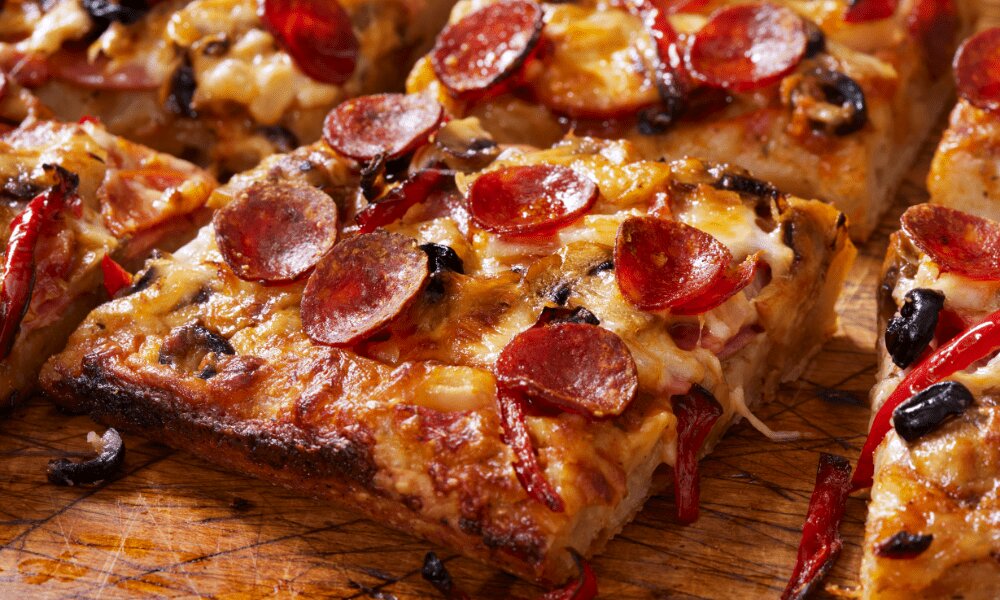 Pizza estilo Detroit recién horneada mostrando la masa dorada y el queso derretido