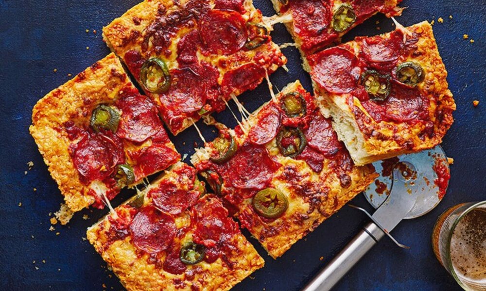 Pizza estilo Detroit en bandeja mostrando los bordes de queso caramelizado